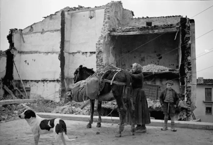 Woman, donkey and child, alongside ruins, Gessopalena, Italy