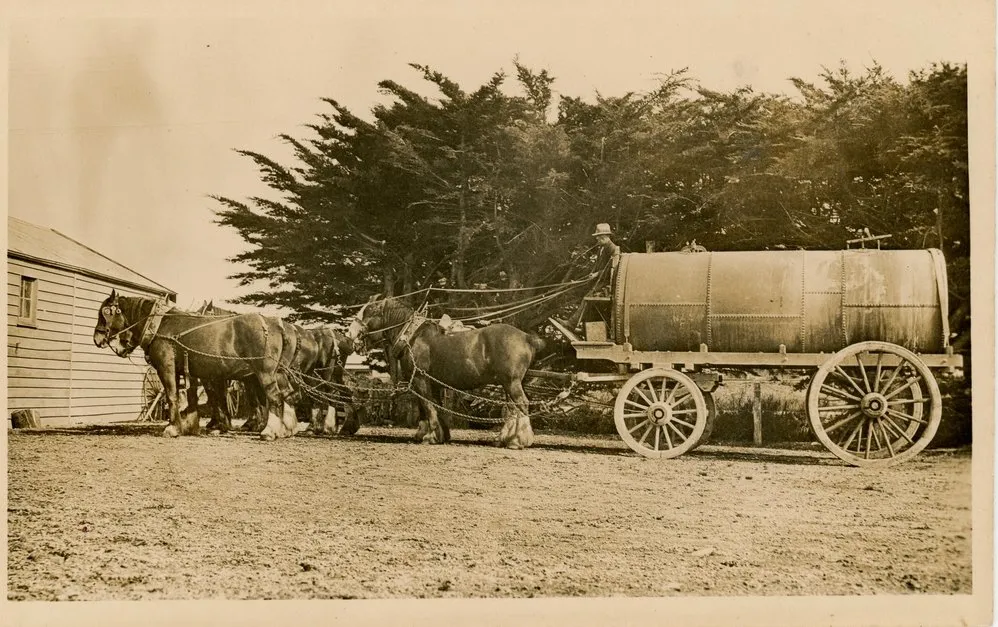 Horse team pulling a wagon with large cyclinder atop