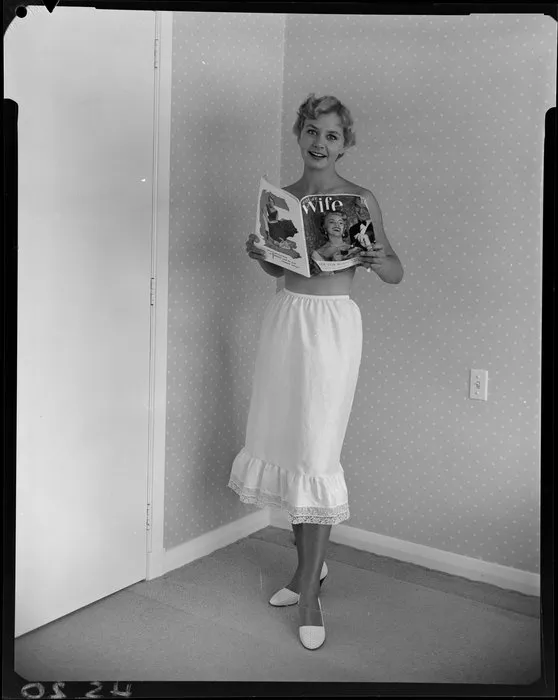 Topless woman in half slip reading 'Wife' magazine