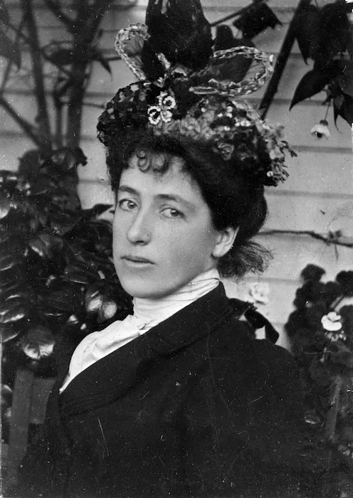 Formal head and shoulders portrait of Frances Mary Hodgkins wearing an ornate hat