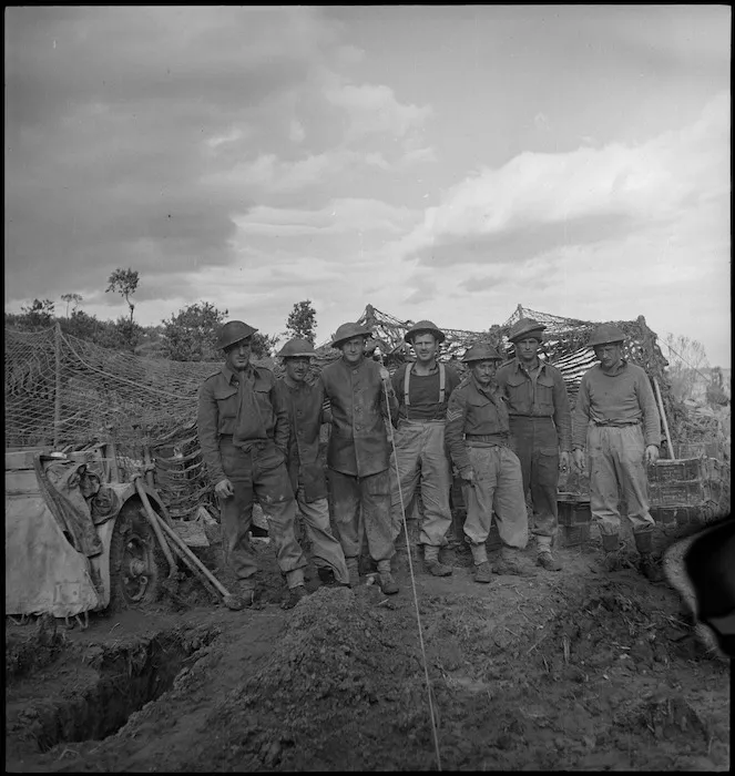 NZ gunners grouped beside their camouflaged gun on the Sangro River front, Italy, World War II - Photograph taken by George Kaye