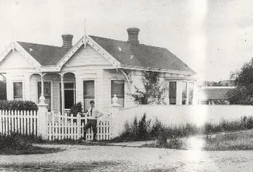 Image: Charles Haigh standing at the gates of an unidentified house