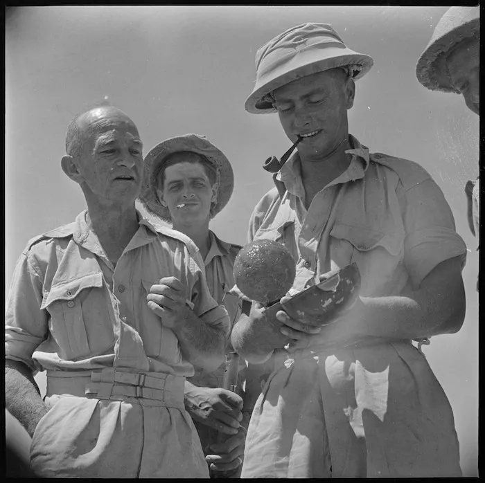 Close up of men examining sticky bomb on the El Alamein front, World War II - Photograph taken by H Paton