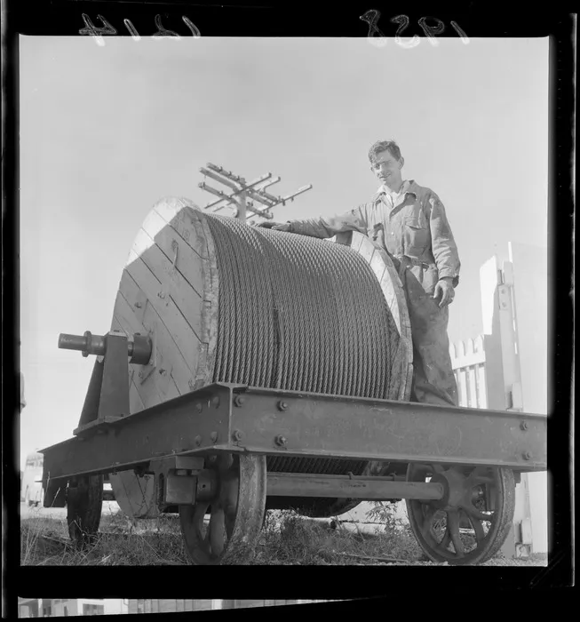 Unidentified man with a large roll of cable to be fitted on the cable car, Wellington