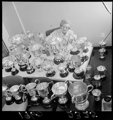 Image: Royal Agricultural Society cups on display with an unidentified older woman, probably Wellington Region