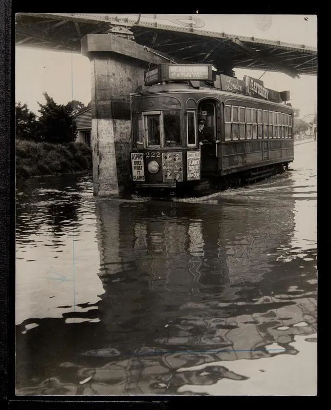 Tram 222 passing under Morningside railway overbridge on flooded road