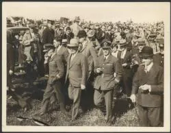Charles Kingsford Smith and Charles Ulm in RAAF uniform, with Mayor of Auckland, George Baildon, walking through crowd after landing at Auckland, New Zealand, September 1928
