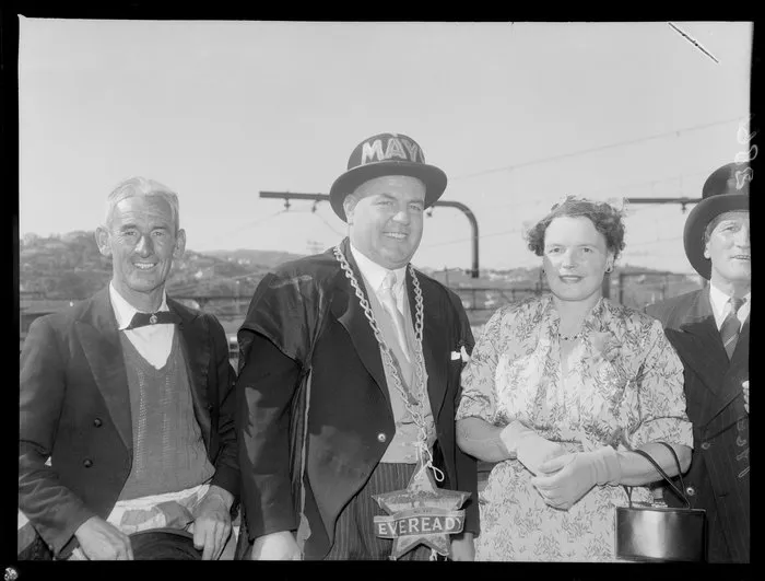 Mr D (Mac) McLachlan 'Mayor of Thorndon', 1956 with chain of office and mayoral hat, and the mayoress with a billy for a handbag