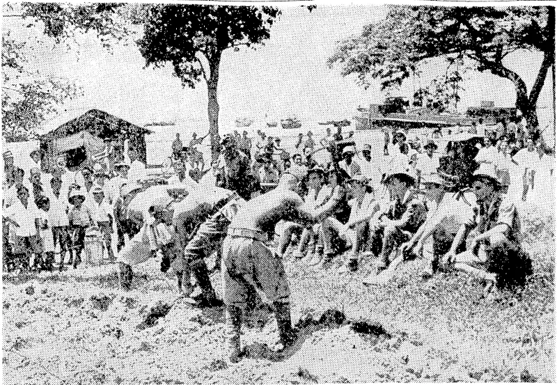 Australian ex-prisoners of ivar, who endured long hours of exposure and hardship ivhilst in Japanese hands, watch Japanese soldiers filling in trenches in Singapore, with the harbour, full of Allied shipping, in the background. (Evening Post, 13 November 1945)