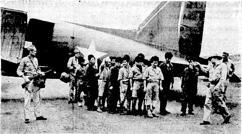 Guarded, by men of the United States army, a squad of Japanese prisoner s-of-war disembark from, an American army transport plane at a United States base in the South Pacific. Some of the Japanese are airmen, wearing their flying kit. (Evening Post, 05 May 1943)