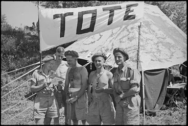 Image: Trying to pick winners before visiting tote at 24 NZ Battalion's aquatic carnival at Arce, Italy, World War II - Photograph taken by George Kaye