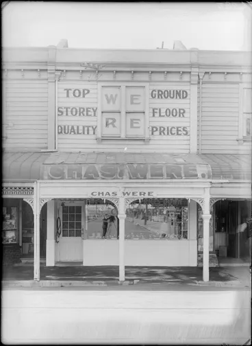 Image: Exterior view of Chas Were butchery, including a reflection of the photographer in the shop window, possibly Christchurch district