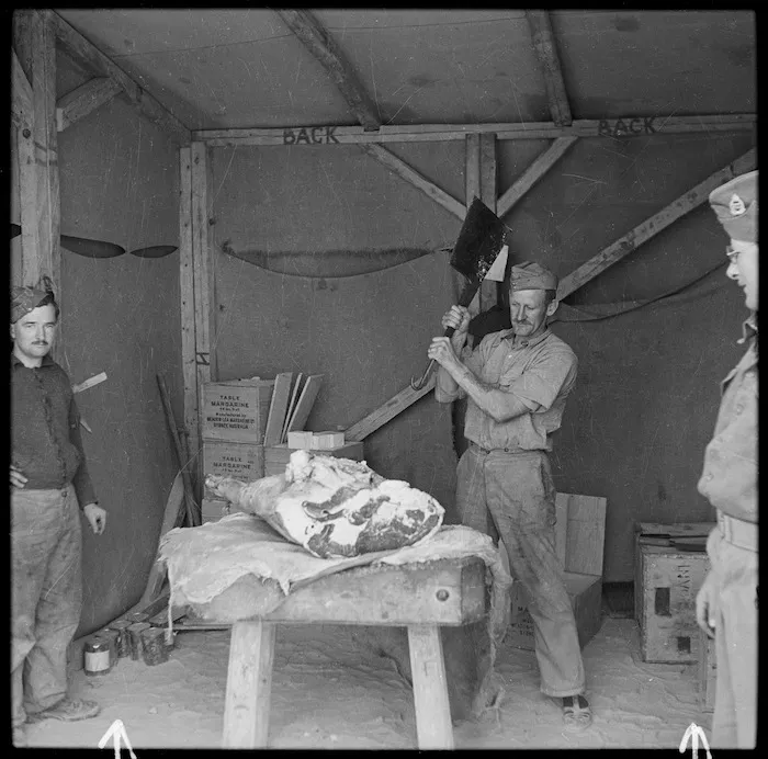Butcher of New Zealand Field Supply depot, wielding a cleaver over a joint of meat