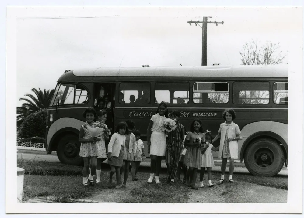 A group of Maori children beside a bus