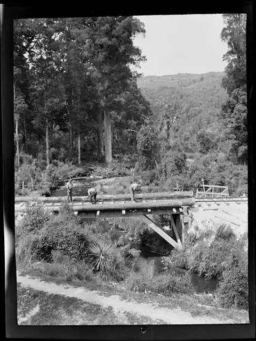 Image: Three unidentified men working on a rail bridge over an unknown stream with forest beyond, Kakahi District, Manawatu-Whanganui Region