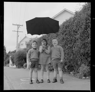 Image: Three unidentified children with an umbrella
