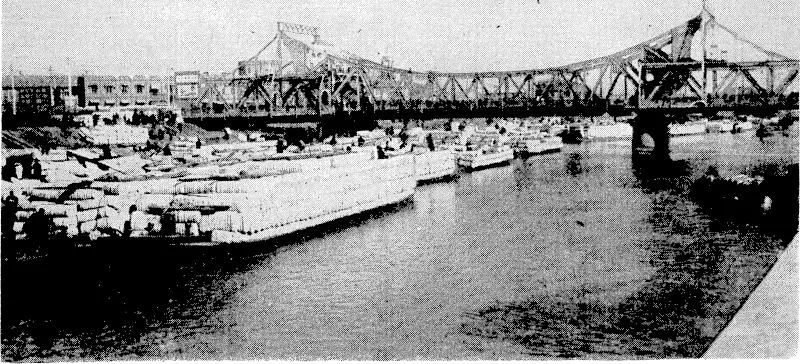 Sport and General" Photo. Tientsin, with the International Bridge, spanning the Hai-Ho River, on which the city stands, in the background. The river is crowded with junks carrying cotton, the major exporting commodity of Tientsin, all tied up as a result of the Japanese blockade. On the right, a view of the throngs of Chinese outside the Concession, ivaitingto be searched and permitted entry by the Japanese authorities* (Evening Post, 25 July 1939)