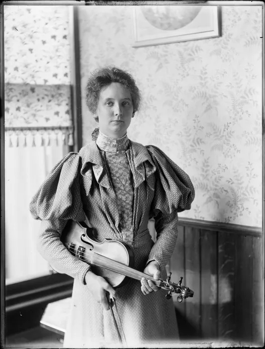 Nellie Devereux holding [viola? violin?], location unknown