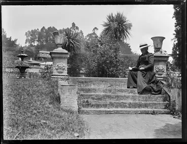 Image: Lydia Williams seated on concrete steps, reading a book, probably at a park [Nelson]