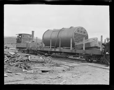 Image: William Williams and an unidentified workman driving a small steam train moving a large steam boiler on a carriage at the Kakahi Settlement Sawmill, Manawatu-Whanganui Region