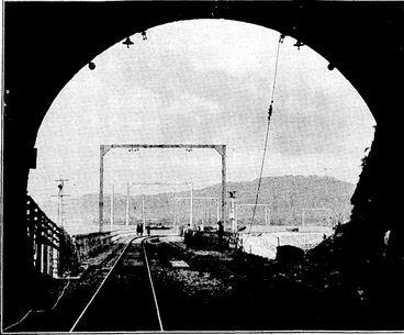 Image: Kvtnnii; ■ l'l'.sf , I'lmlu; ELECTRIFYING THE TAWA FLAT. DEVIATION.—A, view,from the city, portal: of No. 1 tunnel on the Tawa Flat Deviation, show• ing the steel supports for the overhead iviresto be used in connection ' with .the electrification of the line. ' (Evening Post, 15 July 1935)