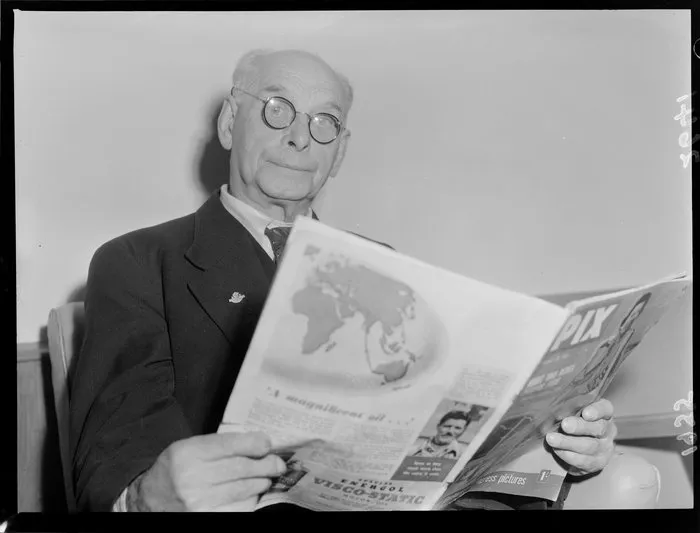 Unidentified man reading at Harry Squires Hostel, Wellington