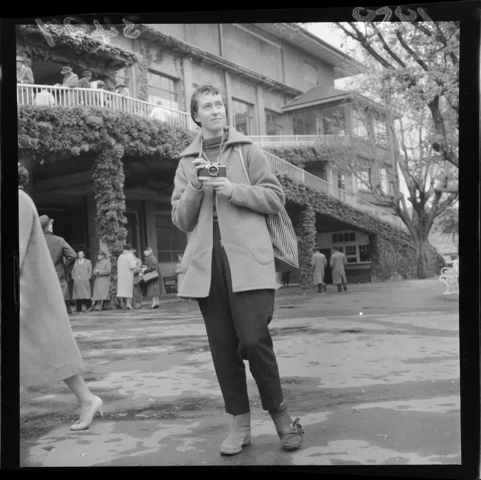 At Trentham Racecourse, Ans Westra with a camera in front of a building, Upper Hutt, Wellington Region