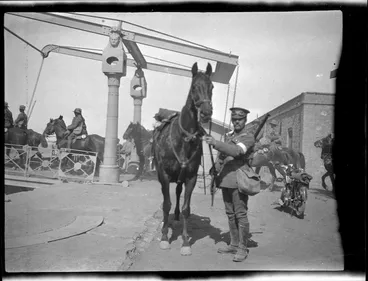 Image: Soldier standing beside his horse.