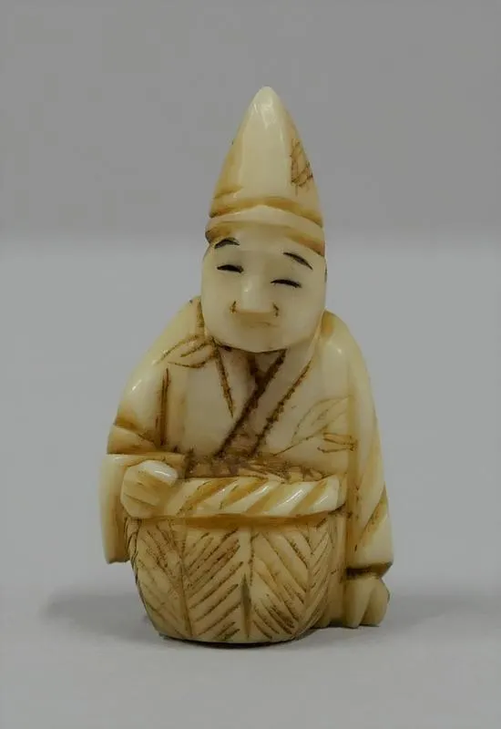Netsuke: Ebisu [Ebisu God]; Netsuke in the form of a man, seated, hatted, with a drum