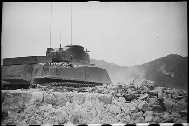 Image: A NZ Sherman tank makes its way through a ruined village in the Cassino area, Italy, World War II - Photograph taken by George Kaye