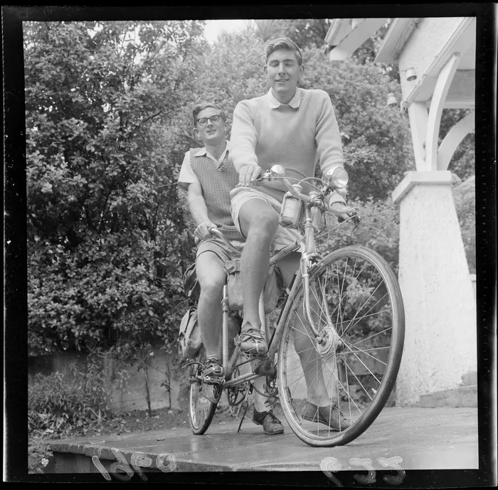 Tony Malcolm and Bill Holmes on a tandem bicycle, cycling around the North and South Islands, in front of an unknown house, Wellington Region