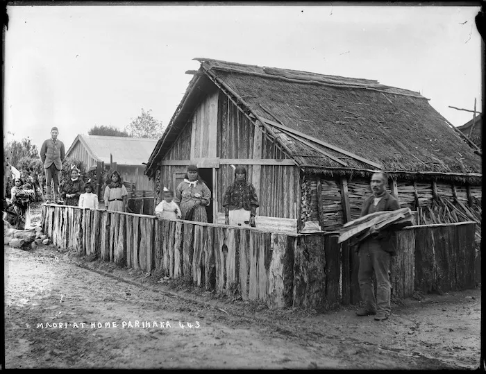 Unidentified people outside a whare on the Parihaka Pa