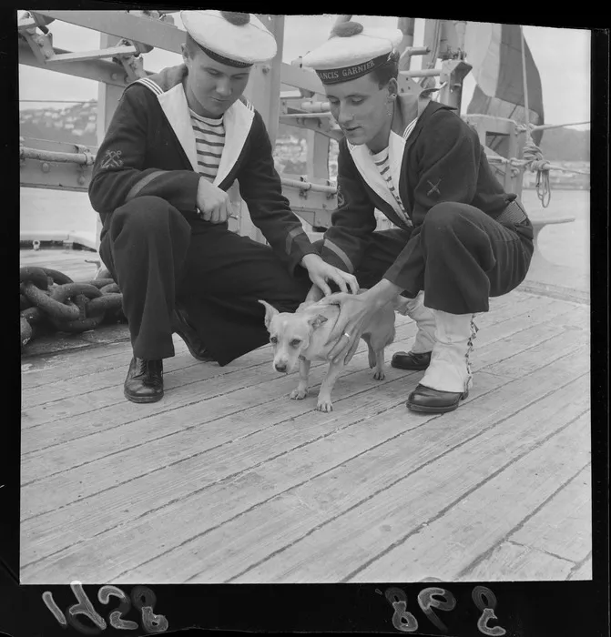 Two crew members of the French navy sloop, Francis Garnier, with the ship's mascot, a dog named Kohgy