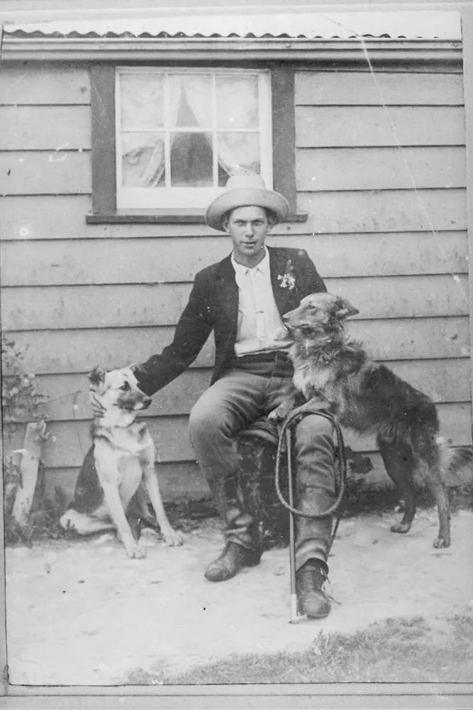Man seated outside a small building, 1909