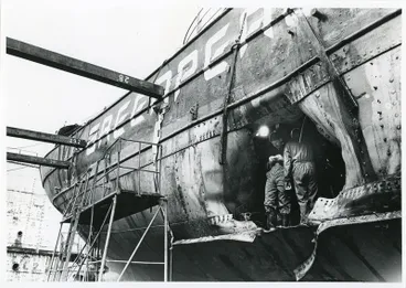 Image: Photograph: Two detectives stand in hole in RAINBOW WARRIOR (1955) following bombing, 1985