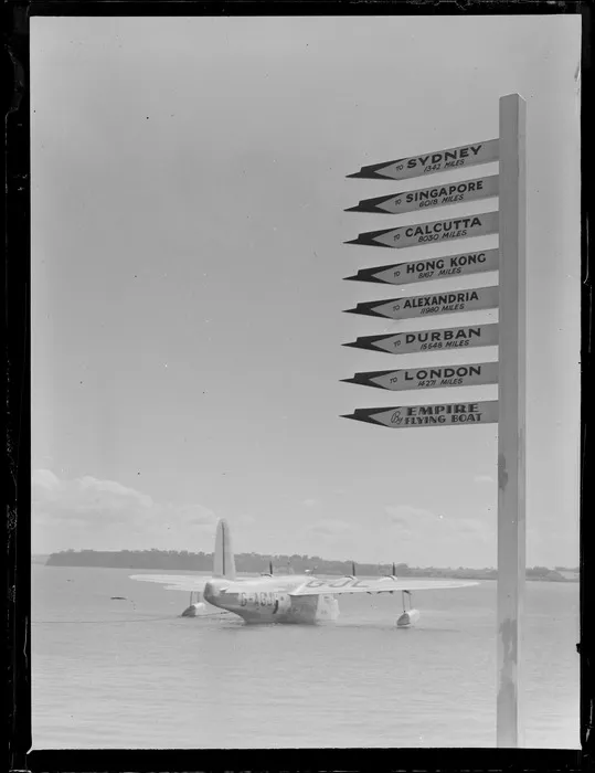 BOAC Hobart G-AGJL, a Short Hythe flying boat, leaving Mechanics Bay, Auckland, includes a directional sign, reading from top downwards "To Sydney 1342 Miles, To Singapore 6018 Miles, To Calcutta 8030 Miles, To Hong Kong 8167 Miles, To Alexandria 11980 Miles, To Durban 15548 Miles, To London 14271 Miles, By Empire Flying Boat"