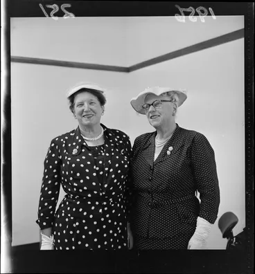 Image: Esther Parsonage and C McKay who are both dressed up in two-piece outfits that include hats, glasses, pearls, brooches and gloves