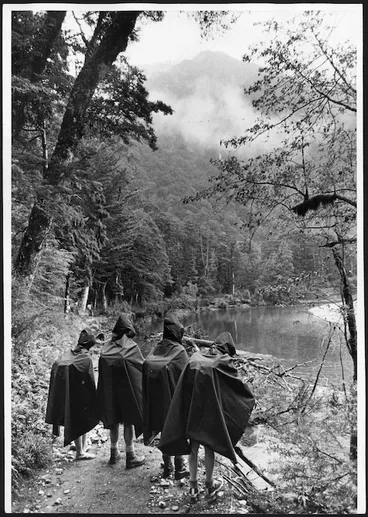 Image: Four walkers in rain capes beside the Clinton River, Milford Track