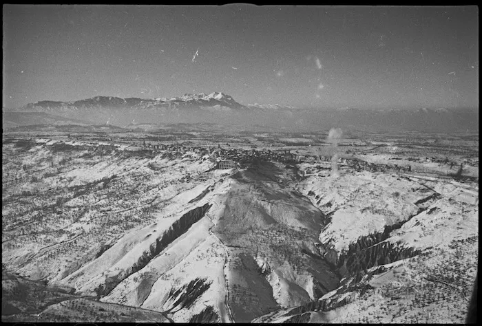 Aerial view of enemy held town of Orsogna, Italy, showing artillery shells bursting in the snow - Photograph taken by G Kaye