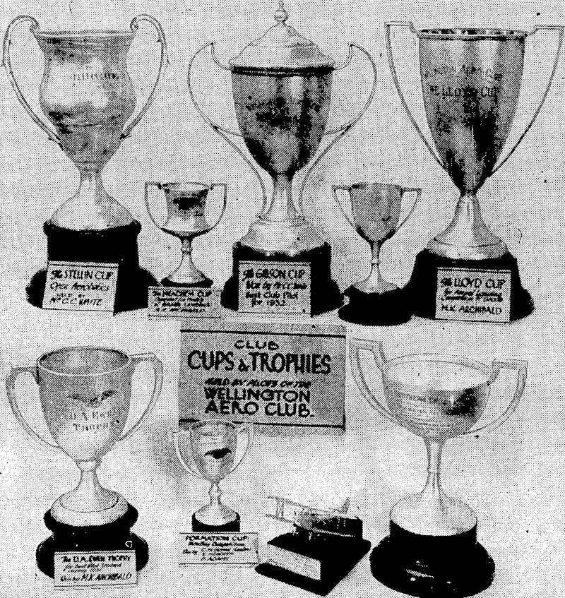Evening Post" Photo. TROPHIESHELD BY; WELLINGTON AERO CLUB.-The Wellington Aero Club may properly.claim to have.had a very bright year as regards the high standard of performance demonstrated by clubtrained pilots in various competitions. In addition to the above trophies the club.'now holds the "New Zealand' Herald" Aviation Cup, open to aero clubs throughout New Zealand. Most of the trophies are for annual competition in such' branches of aviation , as 'formation flying, landing, aerobatics, navigation, etc. (Evening Post, 29 March 1933)