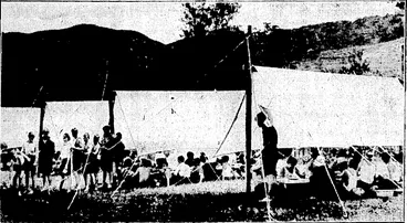 Image: Wellington Studios Plioto. BOYS IN . CAMP.—Scholars from Rongotai Boys' College have been holding their annual camp at Karapoti under the charge of one'of the masters. The picture shows meal-time at the camp. . (Evening Post, 05 January 1935)