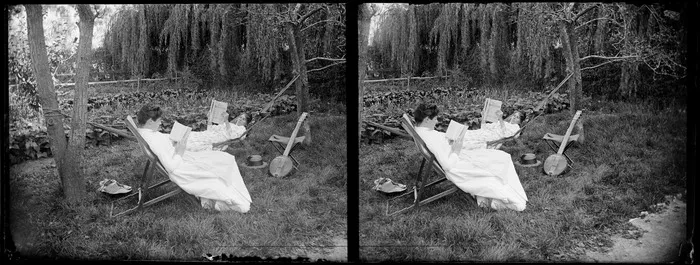 Lydia Myrtle Williams (in hammock) and an unidentified woman in a chair, both of whom are reading, in the garden at the Williams' Carlyle Street home, Napier, Hawkes Bay Region, with vegetable garden in the background