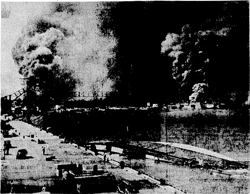 One of the pictures released by the United States military authorities on the anniversary of the treacherous Japanese attack on Pearl Harbour on December 6,194 L Smoke pours from the U.S.S. Shaw, bombed in dry dock (right centre), while in the foreground lies the capsized U.S.S. Oglala, a minelayer. To the left is the 10,000-ton cruiser Helena, struck by an aerial torpedo on the starboard side. The concussion caused the Oglala, then berthed alongside the Helena, to flood, and she turned over when being brought to dock. At the same time, though hardly visible^ in the picture, the battleships Pennsyl-1 vania (a portion of her superstructure is seen on the left) and the Maryland (on the extreme right) were burning fiercely. (Evening Post, 12 January 1943)